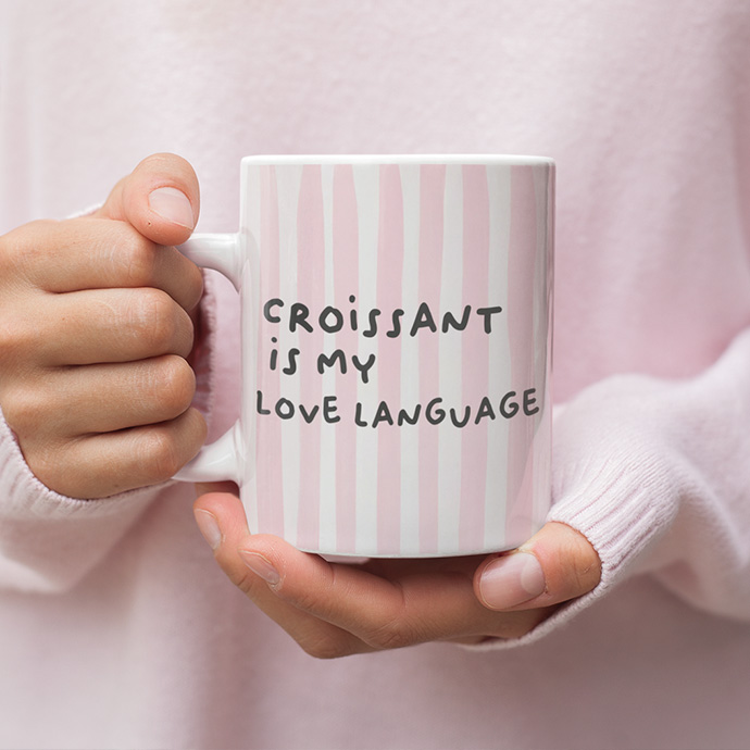 A white mug with a design on it, standing on a surface.
